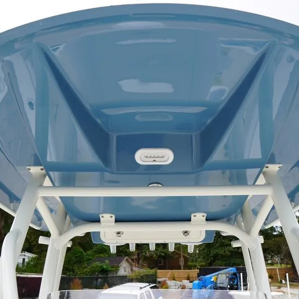 Slide: The Image of 2025 Cobia 220 Center Console boat, blue T-top view, outdoor setting. - 14