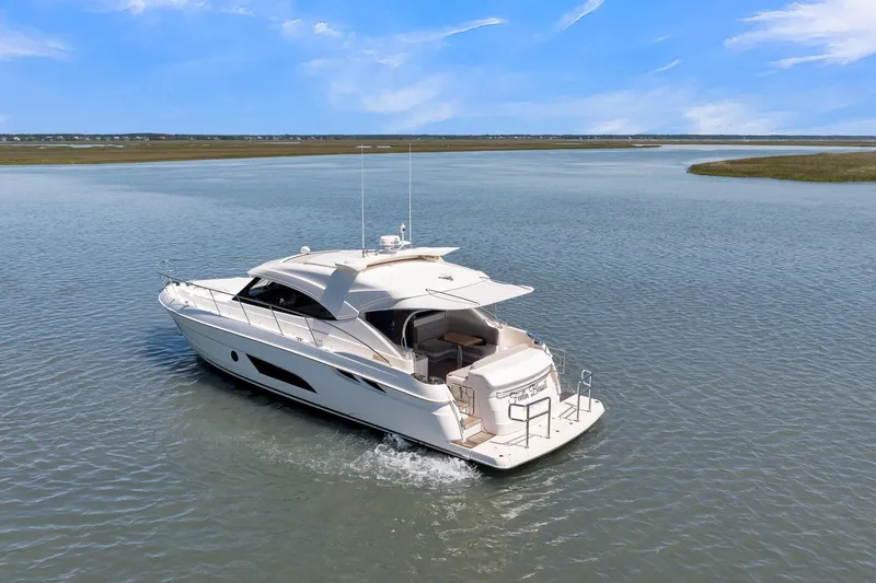 Slide: The Image of 2020 Riviera 4800 Sport Yacht cruising on calm waters under a clear blue sky. - 17