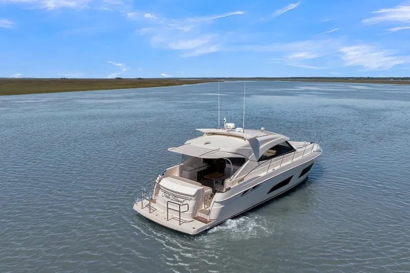 Slide: The Image of 2020 Riviera 4800 Sport Yacht cruising on a serene waterway under a clear blue sky. - 18