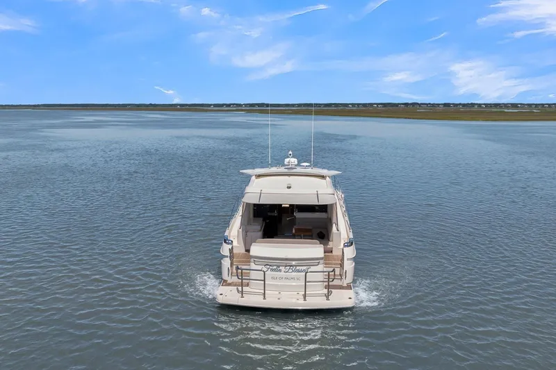Slide: The Image of 2020 Riviera 4800 Sport Yacht cruising on calm waters under a clear blue sky. - 19