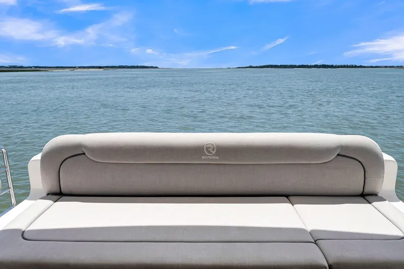 Slide: The Image of 2020 Riviera 4800 Sport Yacht with luxurious seating, overlooking serene ocean view. - 23