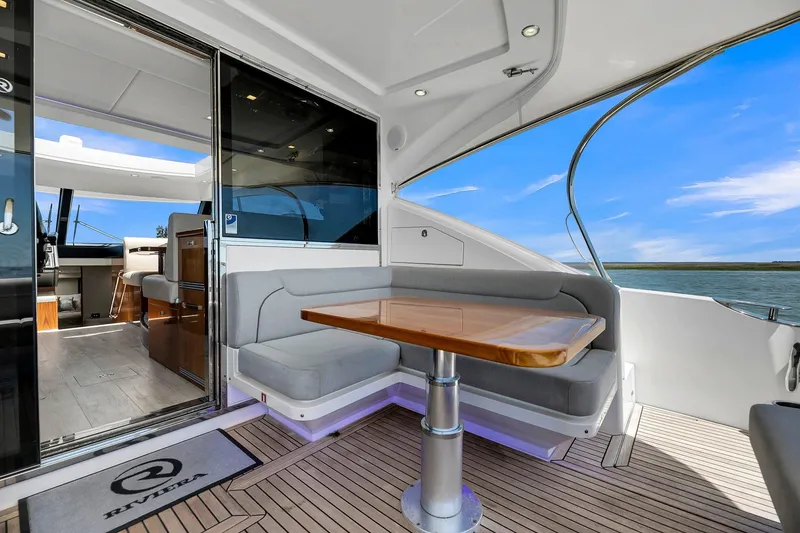Slide: The Image of 2020 Riviera 4800 Sport Yacht interior with elegant seating and ocean view. - 27
