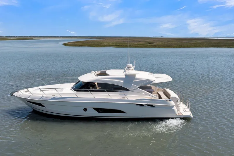 Slide: The Image of 2020 Riviera 4800 Sport Yacht cruising on calm waters under a clear blue sky. - 7