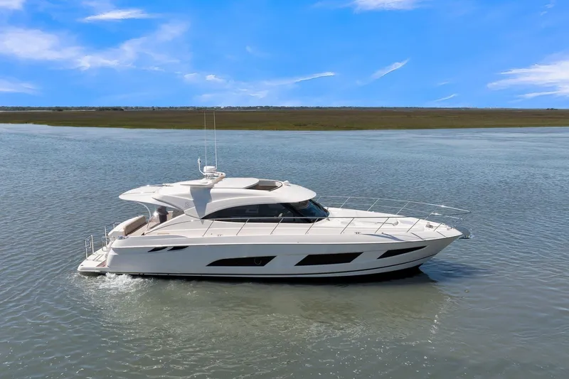 Slide: The Image of 2020 Riviera 4800 Sport Yacht cruising on calm waters under a clear blue sky. - 8