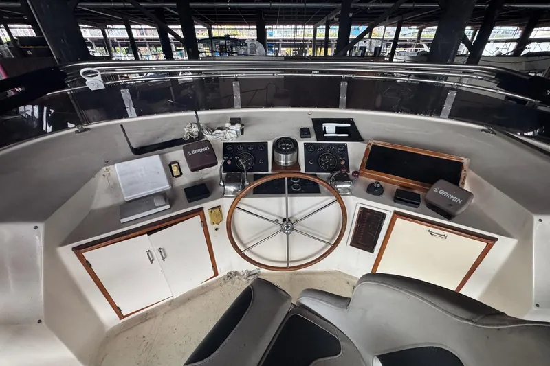 Slide: The Image of 1990 Symbol 53 Sedan boat helm with navigation equipment and steering wheel in a marina setting. - 6