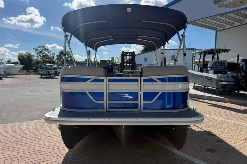 Slide: The Image of 2026 Bennington S 21 SL pontoon boat, blue exterior, parked outdoors under sunny skies. - 3