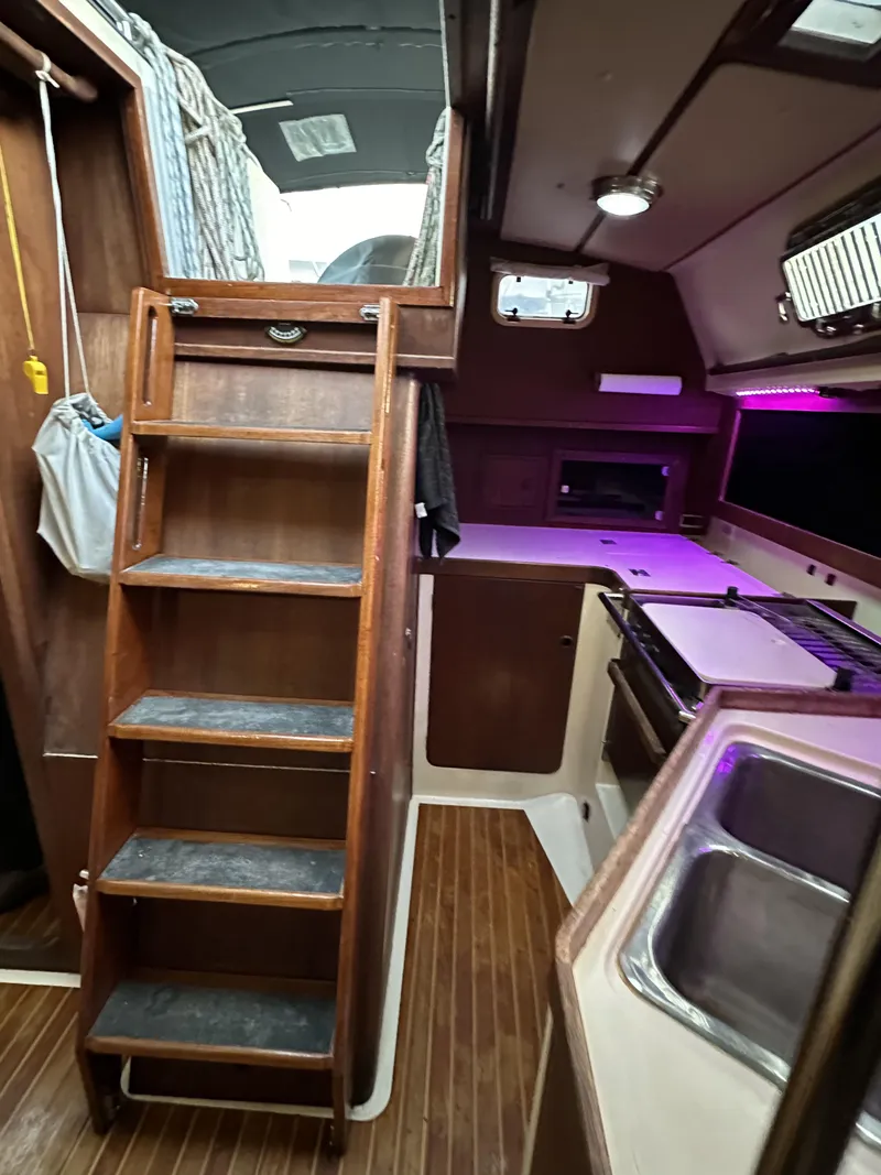 Slide: The Image of 1989 Canadian Sailcraft CS40 interior with wooden ladder, compact kitchen, and modern amenities. - 27