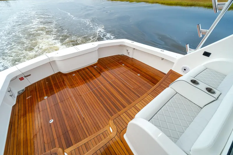 Slide: The Image of 2026 Viking 54 Convertible yacht with teak deck and cushioned seating, cruising on calm waters. - 12