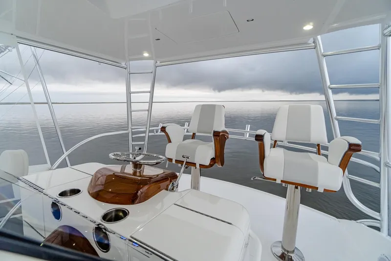 Slide: The Image of 2026 Viking 54 Convertible yacht helm with ocean view, featuring sleek white seating and controls. - 17