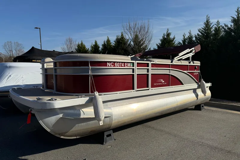 Slide: The Image of 2019 Bennington SX 20 SLX pontoon boat with maroon and silver design, parked outdoors. - 1