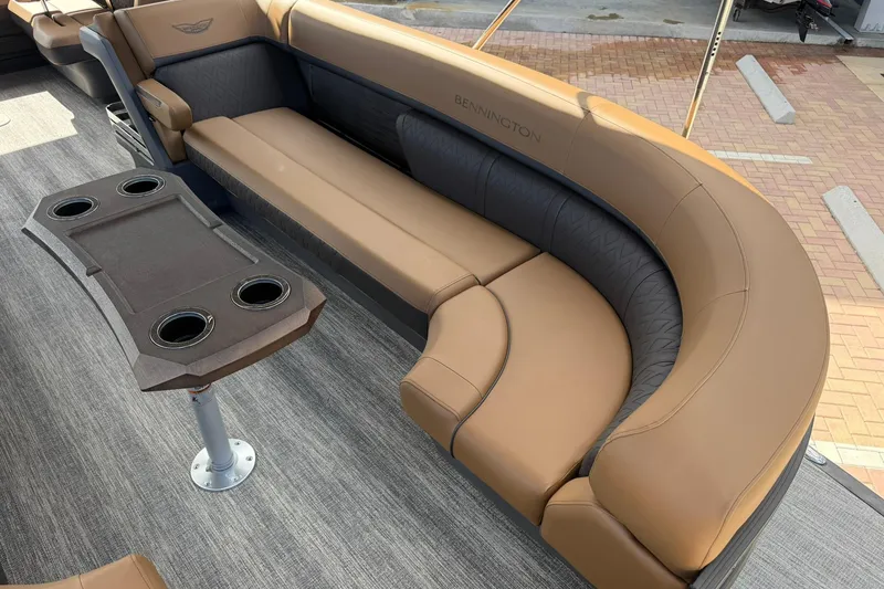 Slide: The Image of 2026 Bennington 26 M Swingback boat interior with tan seating and cupholder table. - 10