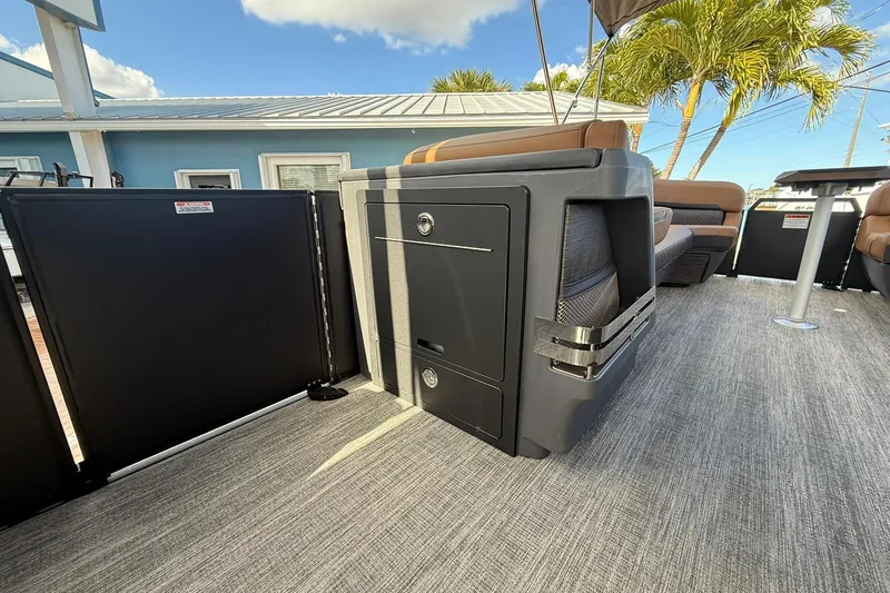 Slide: The Image of 2026 Bennington 26 M Swingback interior with modern seating and storage, under a clear blue sky. - 14