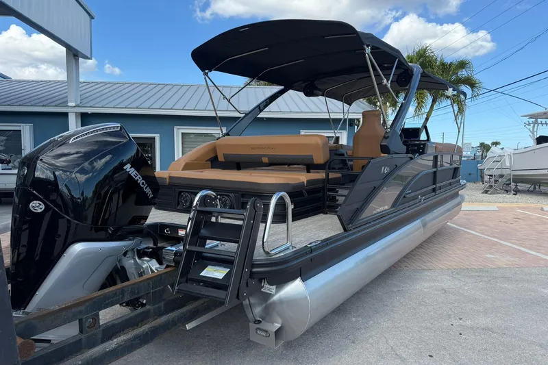 Slide: The Image of 2026 Bennington 26 M Swingback pontoon boat with Mercury engine, docked under blue sky. - 7