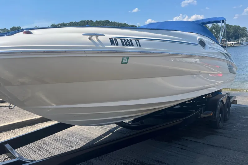 Slide: The Image of 2001 Sea Ray 240 Sundeck boat on trailer by a lake under blue sky. - 10