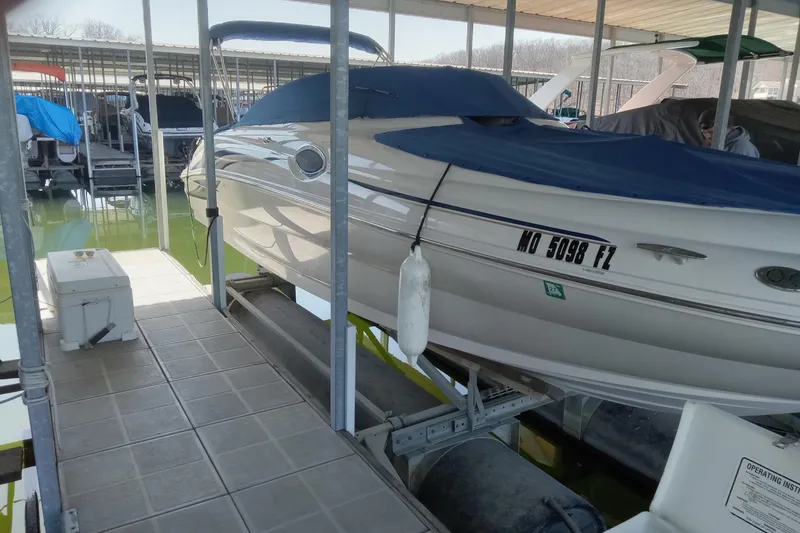 Slide: The Image of 2001 Sea Ray 240 Sundeck boat docked with blue cover in marina. - 2
