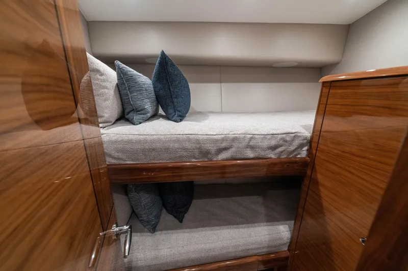 Slide: The Image of 2026 Viking 64 Convertible yacht interior with cozy bunk beds and plush pillows. - 22