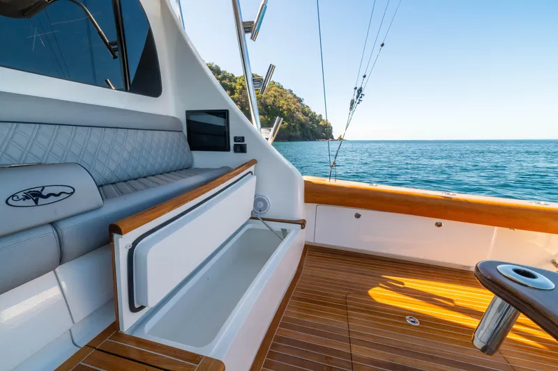 Slide: The Image of 2026 Viking 64 Convertible yacht deck with seating, ocean view, and fishing rods. - 29