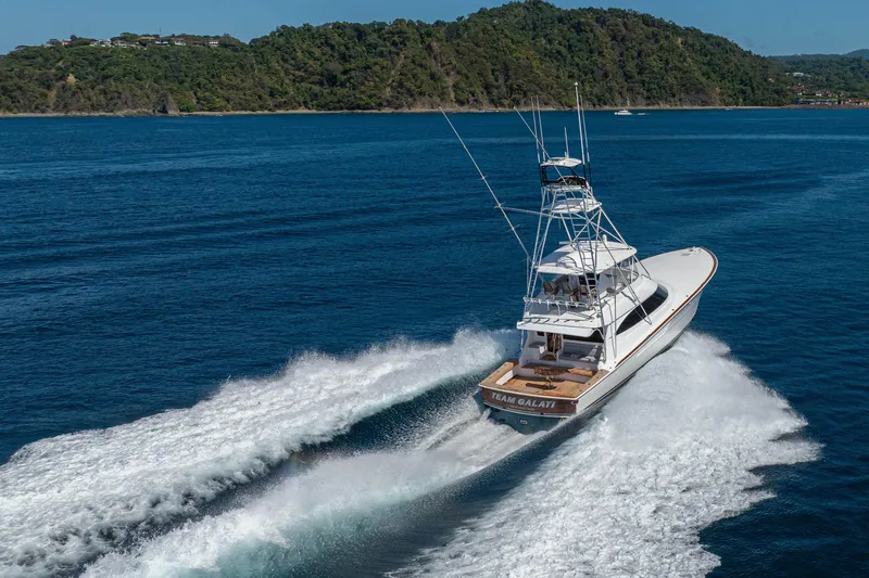 Slide: The Image of 2026 Viking 64 Convertible yacht cruising on blue ocean near lush green island. - 60