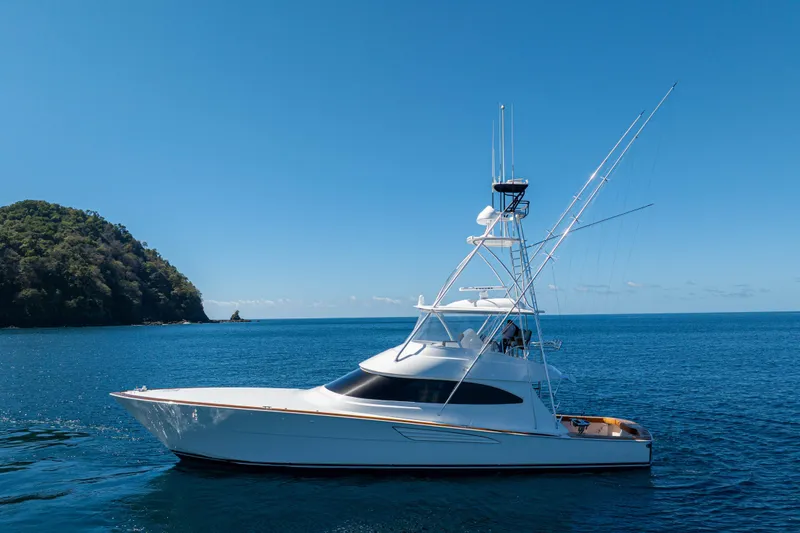 Slide: The Image of 2026 Viking 64 Convertible yacht cruising on blue ocean near lush island. - 63