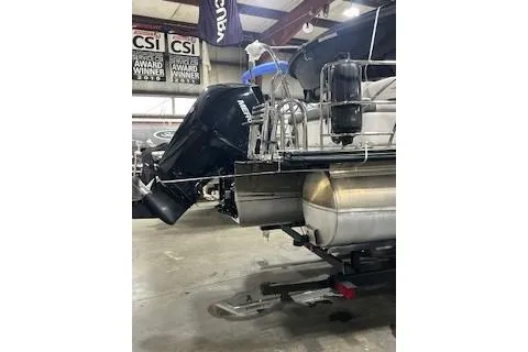 Slide: The Image of 2023 Harris Cruiser 230 pontoon boat in showroom, featuring a powerful outboard motor. - 18