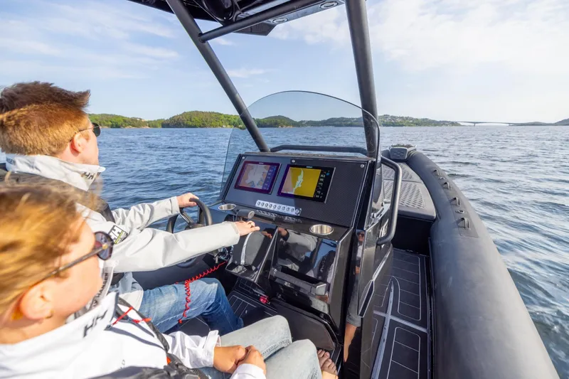 Slide: The Image of Two people navigating a Highfield Sport 900 boat on open water. - 4