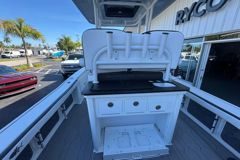 Slide: The Image of 2024 Crevalle 26 HCO boat interior with storage and sink, parked outside dealership. - 13