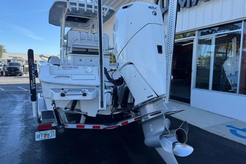 Slide: The Image of 2024 Crevalle 26 HCO boat with powerful outboard motor, parked outside a showroom. - 2
