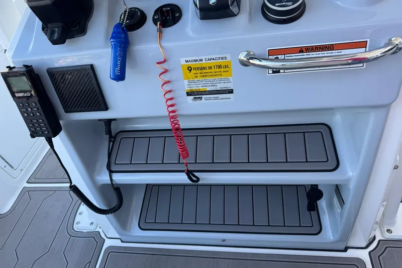 Slide: The Image of 2024 Crevalle 26 HCO boat console with controls, radio, and safety warning labels. - 20