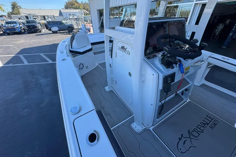 Slide: The Image of 2024 Crevalle 26 HCO boat interior with helm and seating, parked outdoors. - 28