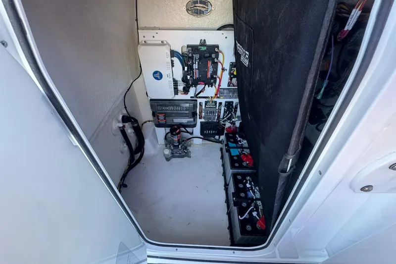 Slide: The Image of 2024 Crevalle 26 HCO boat electrical compartment with batteries and wiring. - 29
