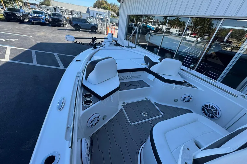 Slide: The Image of 2024 Crevalle 26 HCO boat interior with seating and cup holders, parked outdoors. - 32