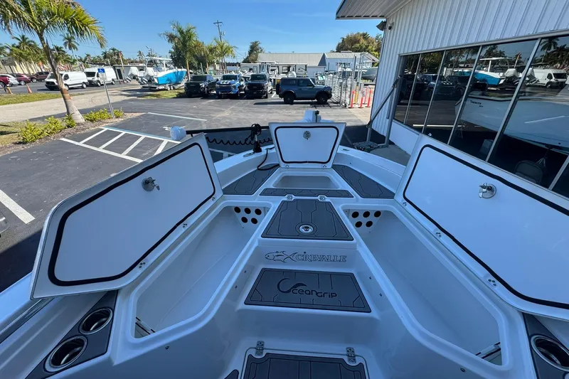 Slide: The Image of 2024 Crevalle 26 HCO boat with open storage compartments, parked outdoors. - 40