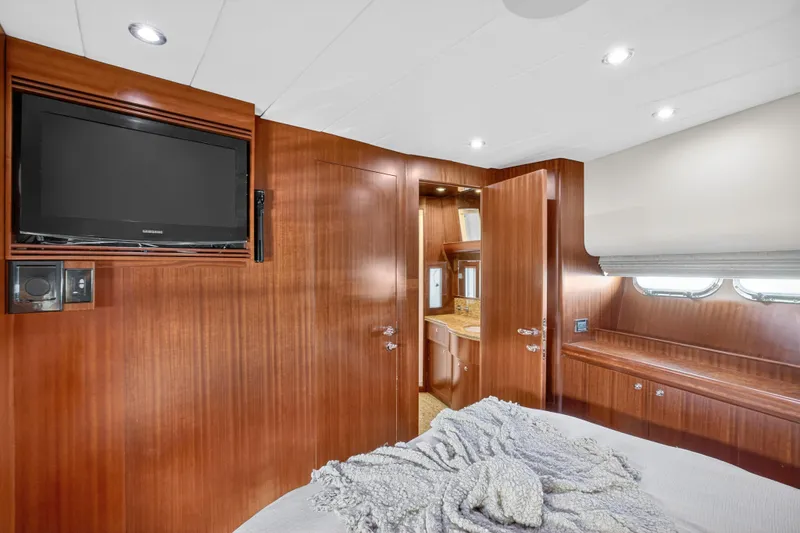Slide: The Image of Luxurious 2009 Horizon Flybridge yacht bedroom with wood paneling, TV, and ensuite bathroom. - 26