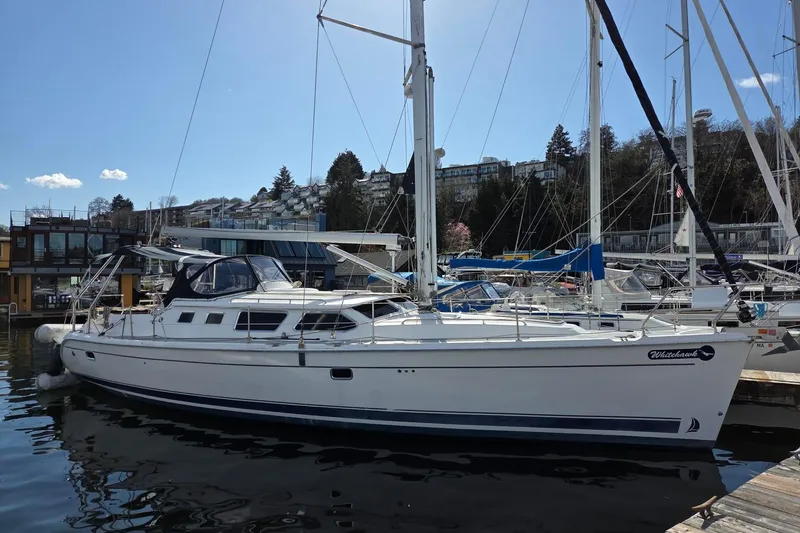 Slide: The Image of 2007 Hunter 44 Deck Salon sailboat docked in a marina, surrounded by other boats. - 23