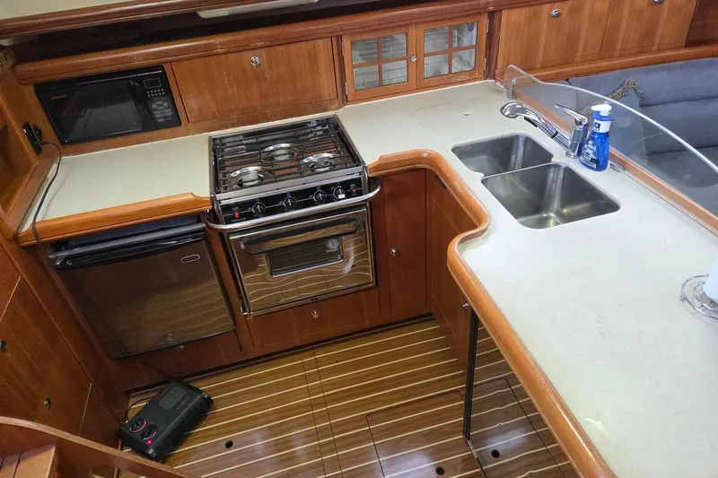 Slide: The Image of 2007 Hunter 44 Deck Salon galley with stove, sink, and microwave in wooden interior. - 25