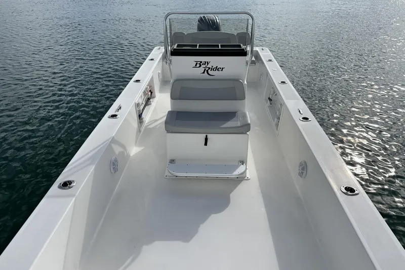 Slide: The Image of 2024 Bay Rider 2460 Skiff on water, showcasing spacious deck and seating. - 13