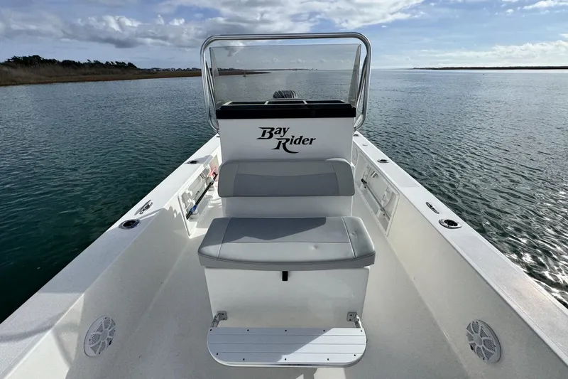 Slide: The Image of 2024 Bay Rider 2460 Skiff on calm water, showcasing seating and console. - 14