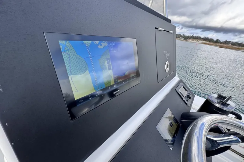 Slide: The Image of 2024 Bay Rider 2460 Skiff dashboard with Garmin navigation system on water. - 18