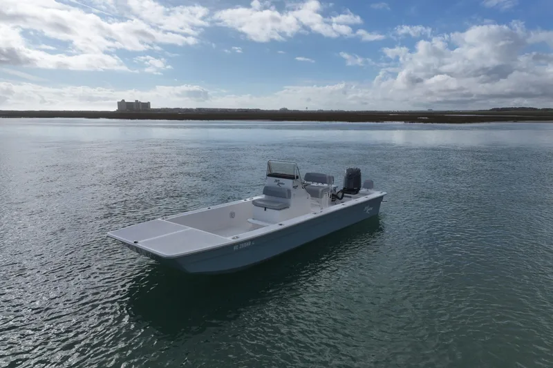 Slide: The Image of 2024 Bay Rider 2460 Skiff on calm water under a partly cloudy sky. - 2