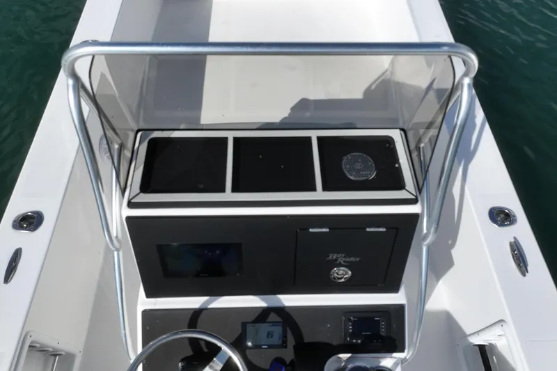 Slide: The Image of 2024 Bay Rider 2460 Skiff console with steering wheel and controls on water. - 20