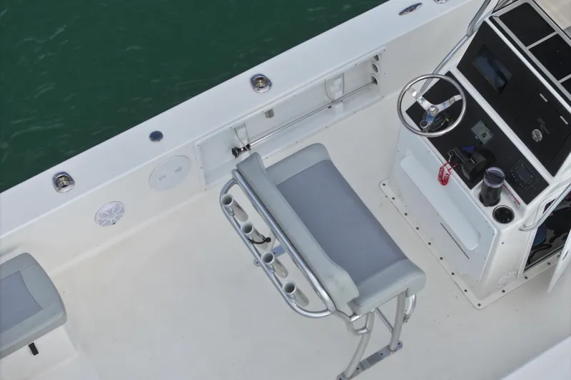 Slide: The Image of 2024 Bay Rider 2460 Skiff interior with steering console and seating, on calm water. - 21
