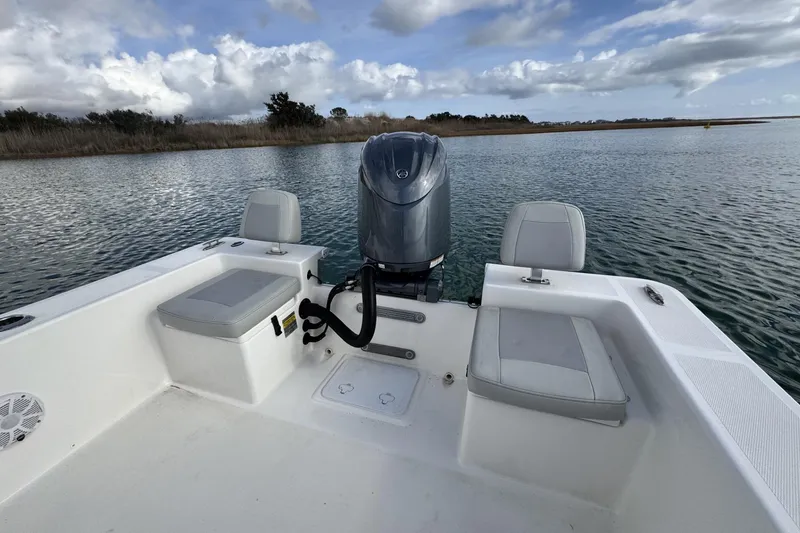 Slide: The Image of 2024 Bay Rider 2460 Skiff on calm water, showcasing seating and motor. - 23