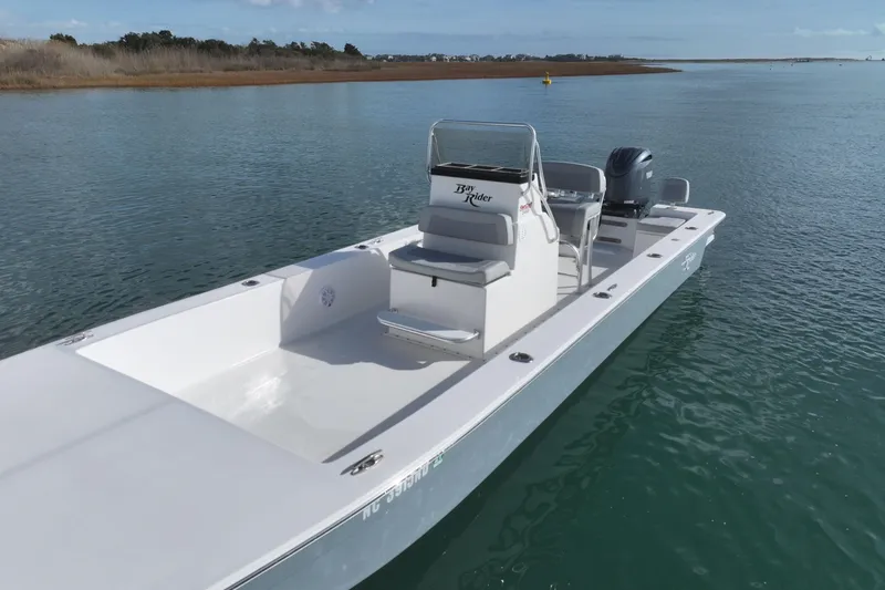 Slide: The Image of 2024 Bay Rider 2460 Skiff on calm water, showcasing sleek design and spacious deck. - 4