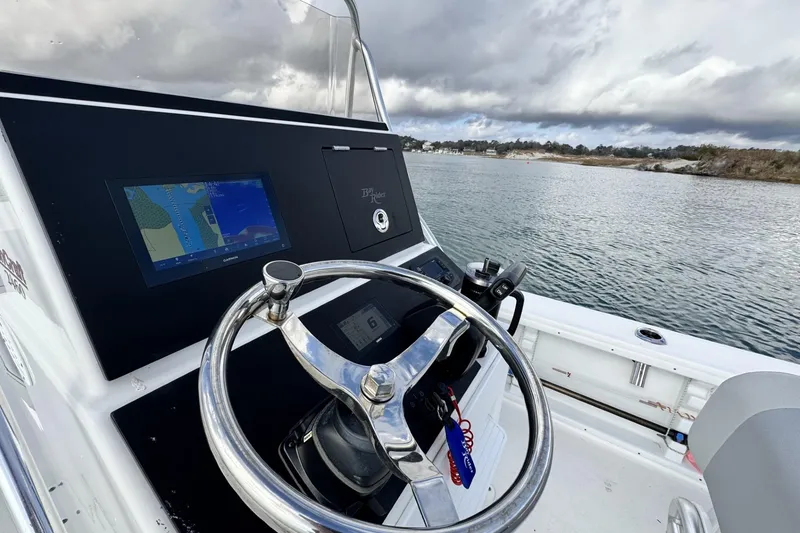 Slide: The Image of 2024 Bay Rider 2460 Skiff steering console with navigation screen on a calm waterway. - 7
