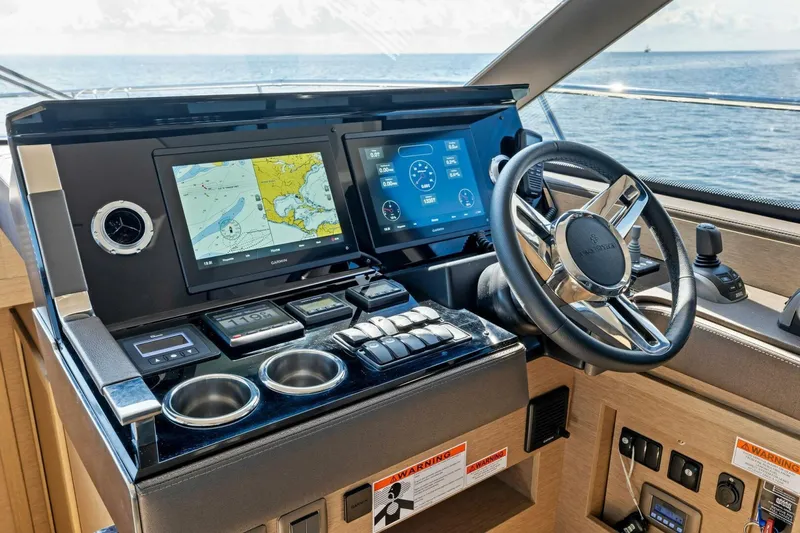 Slide: The Image of Prestige 460 Flybridge 2023 helm with navigation screens and steering wheel, overlooking the ocean. - 16