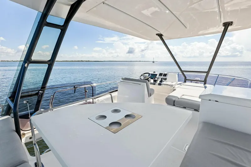 Slide: The Image of Luxury 2023 Prestige 460 yacht interior with ocean view, featuring modern seating and navigation area. - 53