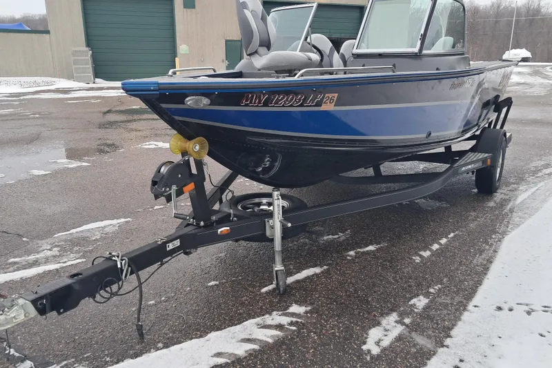 Slide: The Image of 2015 Alumacraft Trophy 175 boat on trailer in snowy parking lot. - 1
