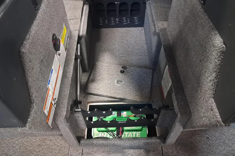 Slide: The Image of 2015 Alumacraft Trophy 175 boat interior storage compartment with battery and carpeted finish. - 19