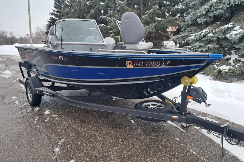 Slide: The Image of 2015 Alumacraft Trophy 175 boat on trailer, parked on snowy road. - 2
