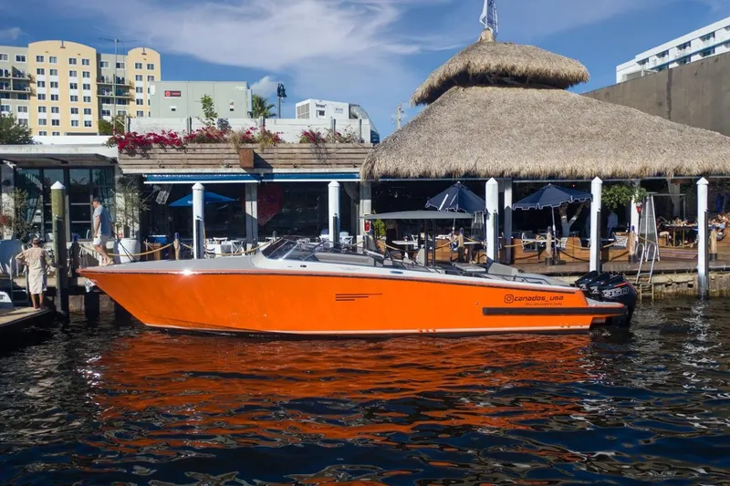 Slide: The Image of 2026 Canados 431 Speedster, orange, docked at a waterfront restaurant. - 4